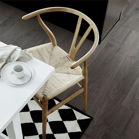 lähikuva tuolista, jossa on kahvimuki pöydällä ja musta laminaattilattia